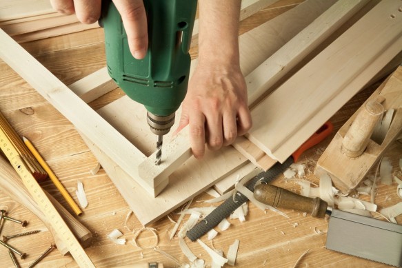 9568933 - wooden workshop table with tools. man's arms drill plank.